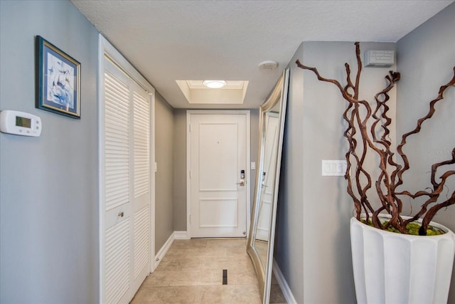 entryway with a skylight, light tile floors, and a textured ceiling