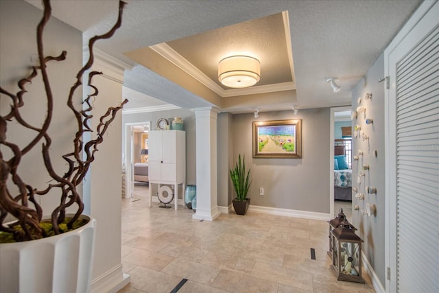 interior space featuring a textured ceiling, ornamental molding, a tray ceiling, and decorative columns