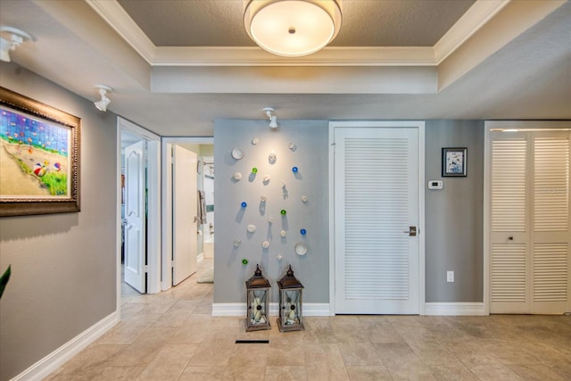 hallway featuring a raised ceiling, crown molding, and light tile floors