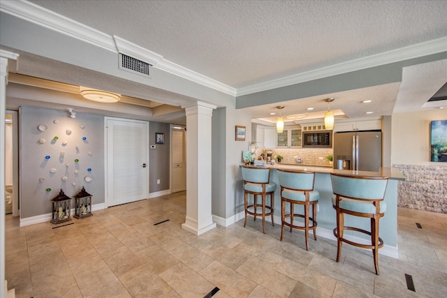 kitchen featuring white cabinets, tasteful backsplash, decorative light fixtures, stainless steel fridge, and kitchen peninsula