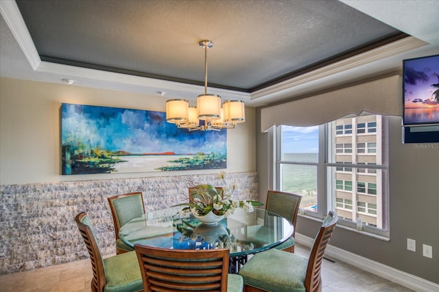 tiled dining area featuring ornamental molding, a textured ceiling, a notable chandelier, and a tray ceiling