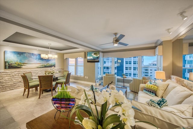 living room featuring ceiling fan with notable chandelier, crown molding, tile flooring, and a raised ceiling