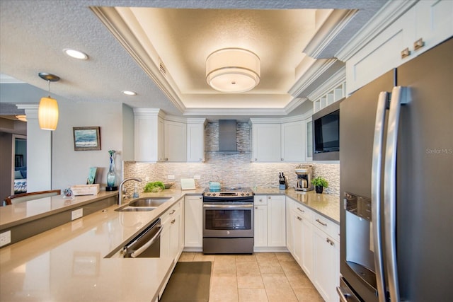 kitchen with wall chimney exhaust hood, white cabinetry, backsplash, appliances with stainless steel finishes, and a raised ceiling