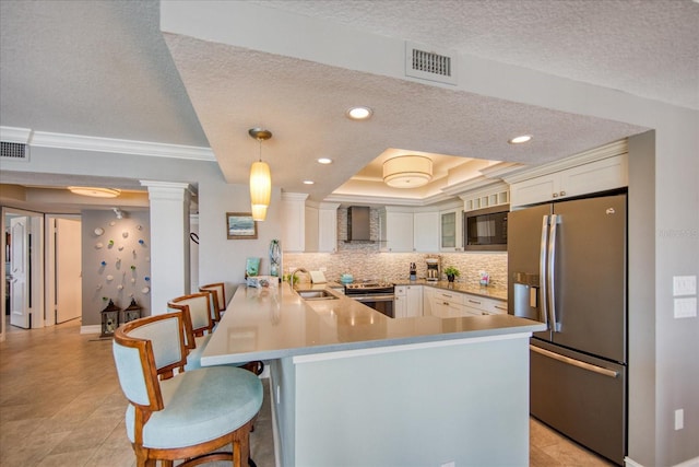 kitchen featuring hanging light fixtures, ornamental molding, backsplash, appliances with stainless steel finishes, and wall chimney range hood