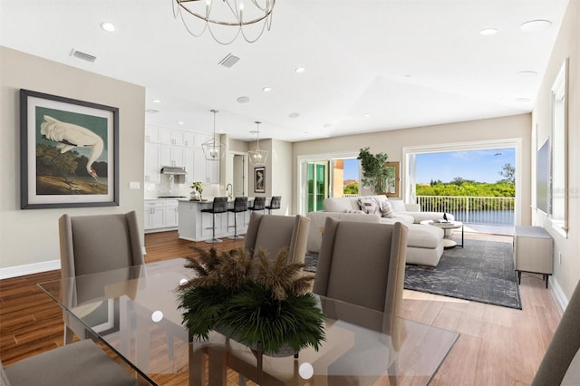 dining space with light hardwood / wood-style floors and an inviting chandelier