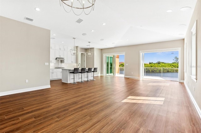 unfurnished living room with an inviting chandelier and light hardwood / wood-style flooring