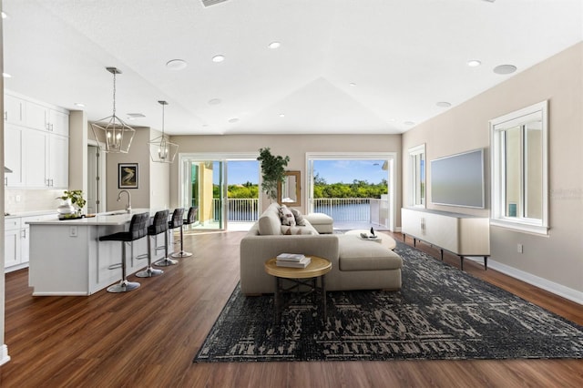 living room with dark hardwood / wood-style flooring, sink, and a chandelier