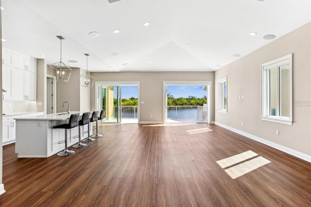 kitchen featuring a kitchen breakfast bar, a chandelier, white cabinetry, dark hardwood / wood-style floors, and decorative light fixtures