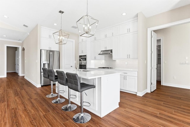 kitchen featuring dark hardwood / wood-style flooring, appliances with stainless steel finishes, tasteful backsplash, white cabinets, and crown molding