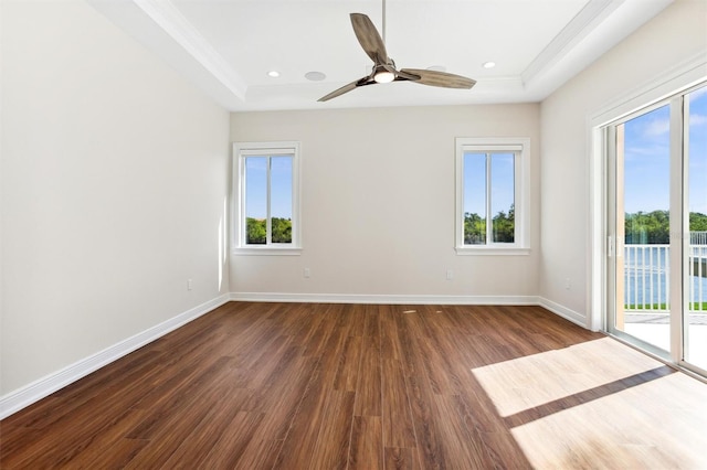 unfurnished room featuring dark hardwood / wood-style flooring, ceiling fan, and a raised ceiling