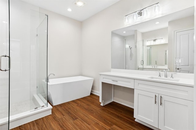 bathroom with hardwood / wood-style floors, independent shower and bath, and vanity