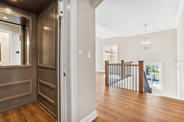 hallway featuring an inviting chandelier, ornamental molding, and hardwood / wood-style flooring