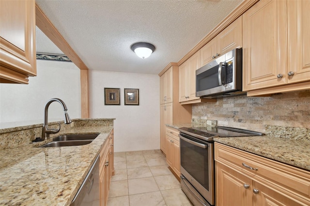 kitchen featuring appliances with stainless steel finishes, sink, light stone counters, and light tile floors