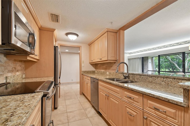 kitchen with light stone counters, stainless steel appliances, light tile floors, a textured ceiling, and sink