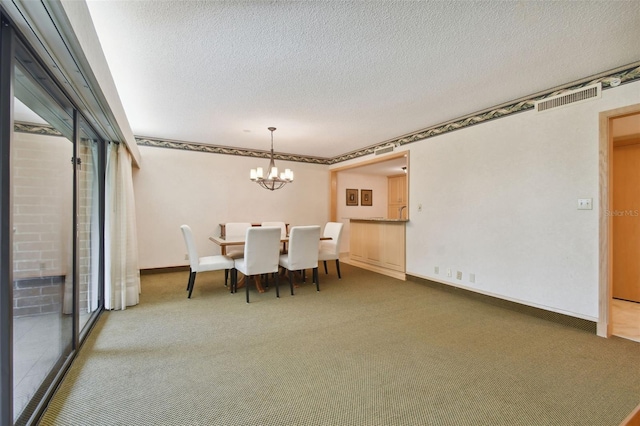 dining space featuring an inviting chandelier, a textured ceiling, and dark colored carpet