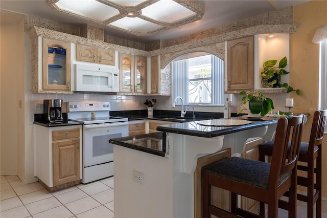 kitchen featuring tasteful backsplash, kitchen peninsula, light tile patterned floors, white appliances, and sink