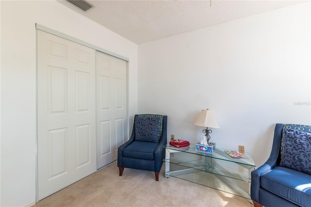 sitting room with a textured ceiling and light carpet