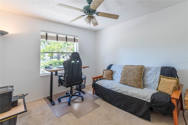 office area with ceiling fan, a textured ceiling, a healthy amount of sunlight, and light carpet