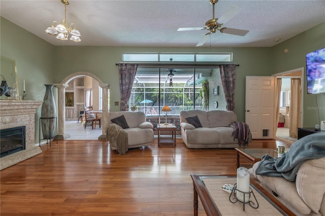 living room with light hardwood / wood-style flooring, a textured ceiling, decorative columns, and ceiling fan with notable chandelier