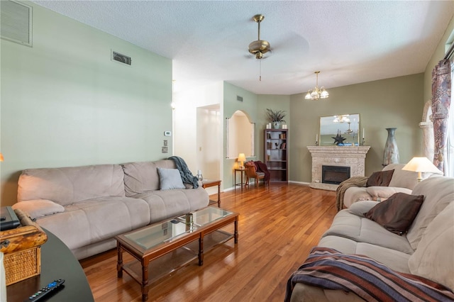 living room with a textured ceiling, ceiling fan with notable chandelier, and light hardwood / wood-style floors