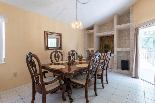 tiled dining room featuring lofted ceiling, a stone fireplace, and an inviting chandelier