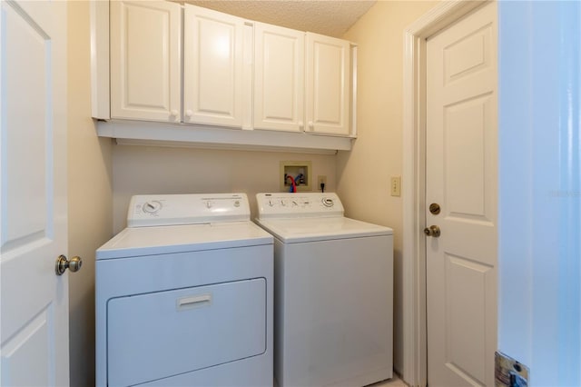 laundry area featuring washing machine and dryer, a textured ceiling, and cabinets