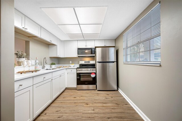 kitchen featuring white cabinets, sink, appliances with stainless steel finishes, and light hardwood / wood-style flooring