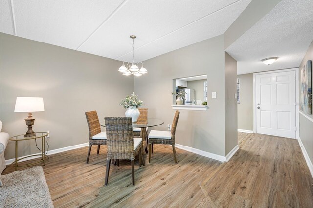 dining space featuring a textured ceiling, hardwood / wood-style flooring, and a chandelier