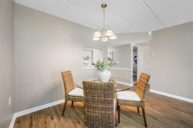 dining space featuring hardwood / wood-style flooring, a textured ceiling, and a chandelier