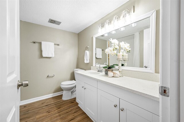 bathroom with oversized vanity, hardwood / wood-style flooring, toilet, and a textured ceiling