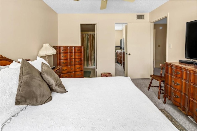 bedroom with ceiling fan, carpet, ensuite bathroom, and a textured ceiling