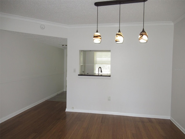 interior space with a sink, a textured ceiling, baseboards, and wood finished floors