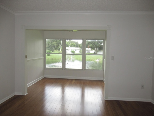 spare room featuring ornamental molding, dark wood-style flooring, a wealth of natural light, and baseboards