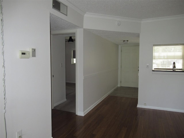 interior space featuring ornamental molding, visible vents, a textured ceiling, and wood finished floors