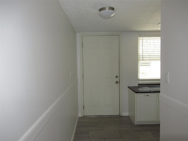 hall with a textured ceiling and baseboards