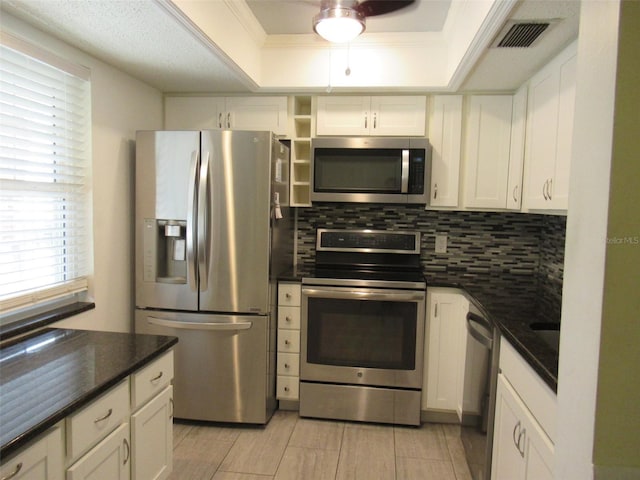 kitchen featuring a tray ceiling, tasteful backsplash, visible vents, appliances with stainless steel finishes, and white cabinets