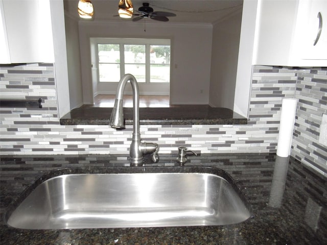 details with decorative backsplash, dark stone countertops, a sink, and crown molding