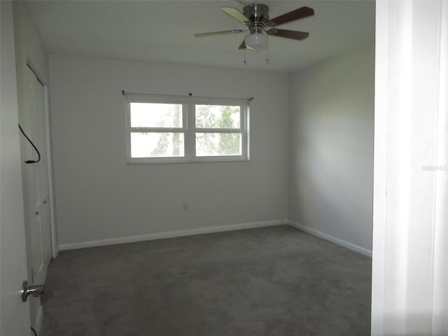 carpeted spare room featuring a ceiling fan and baseboards