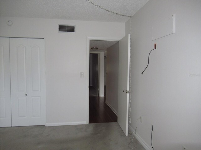 unfurnished bedroom featuring a closet, visible vents, a textured ceiling, and baseboards