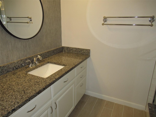 bathroom featuring wood finish floors, vanity, and baseboards