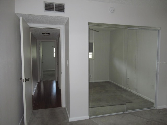 interior space with a textured ceiling, visible vents, and baseboards