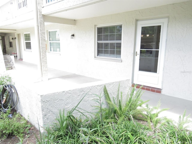 doorway to property with a balcony and stucco siding