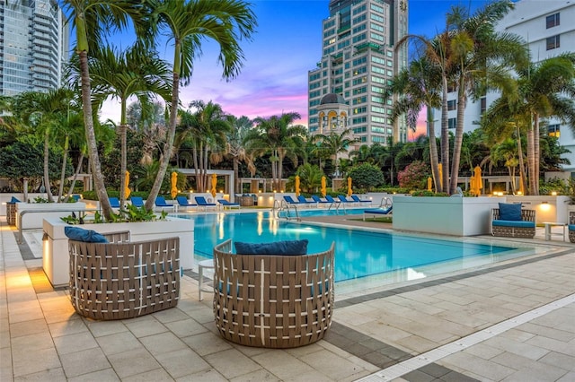 pool at dusk featuring a patio area