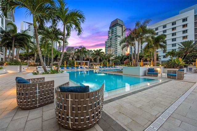 pool at dusk with a patio area