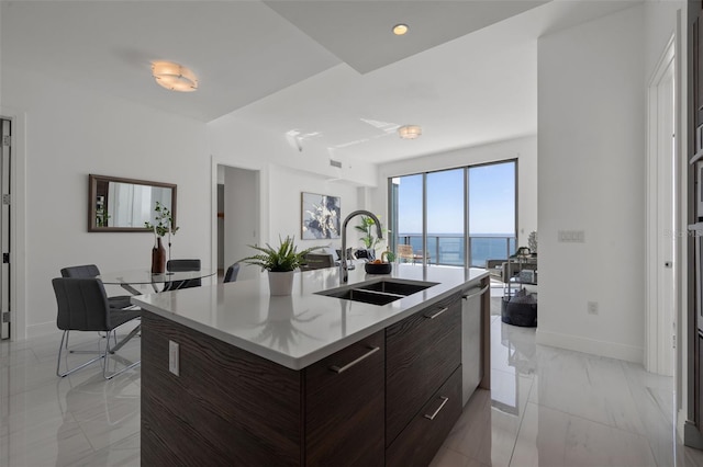 kitchen featuring sink, a water view, light tile flooring, stainless steel dishwasher, and dark brown cabinets