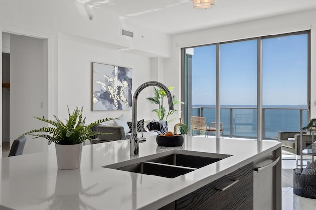 kitchen featuring a water view, sink, and light stone counters