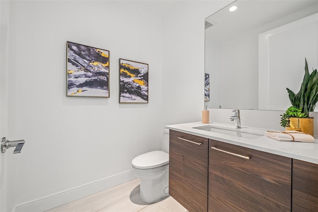 bathroom featuring toilet, vanity, and hardwood / wood-style floors