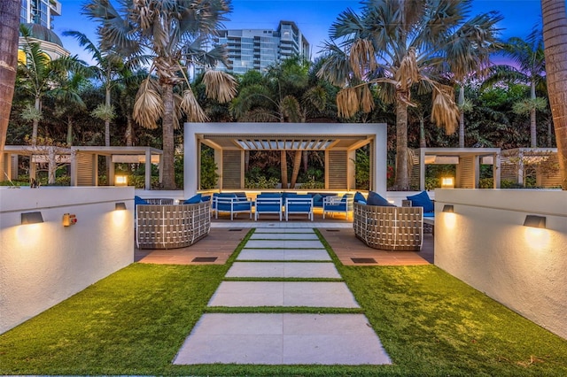 patio terrace at dusk with area for grilling and a pergola