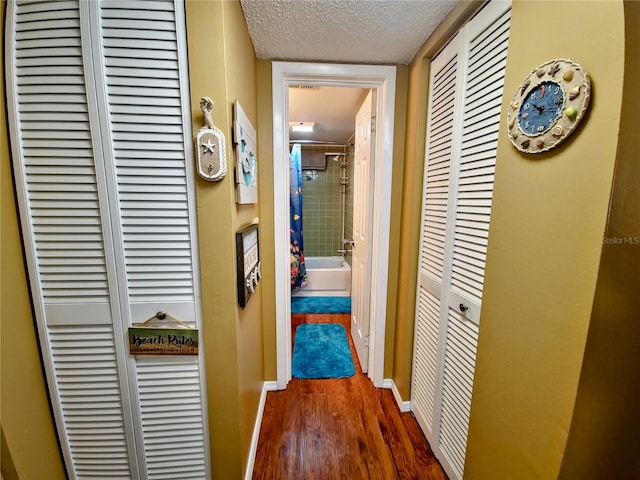 hallway with dark hardwood / wood-style flooring and a textured ceiling