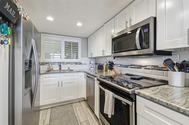 kitchen featuring backsplash, white cabinetry, appliances with stainless steel finishes, and light stone counters